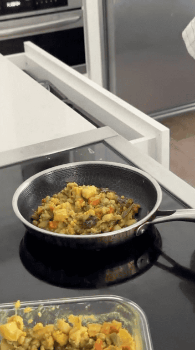 Placing the leftover veg curry into the pan.  