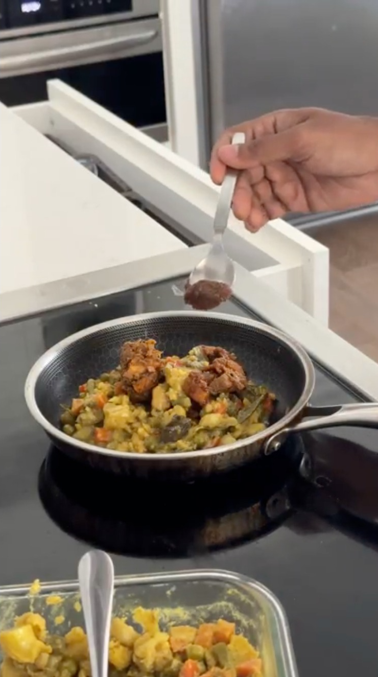 A spoon of beef bouillon is being added to the leftover veg curry.
