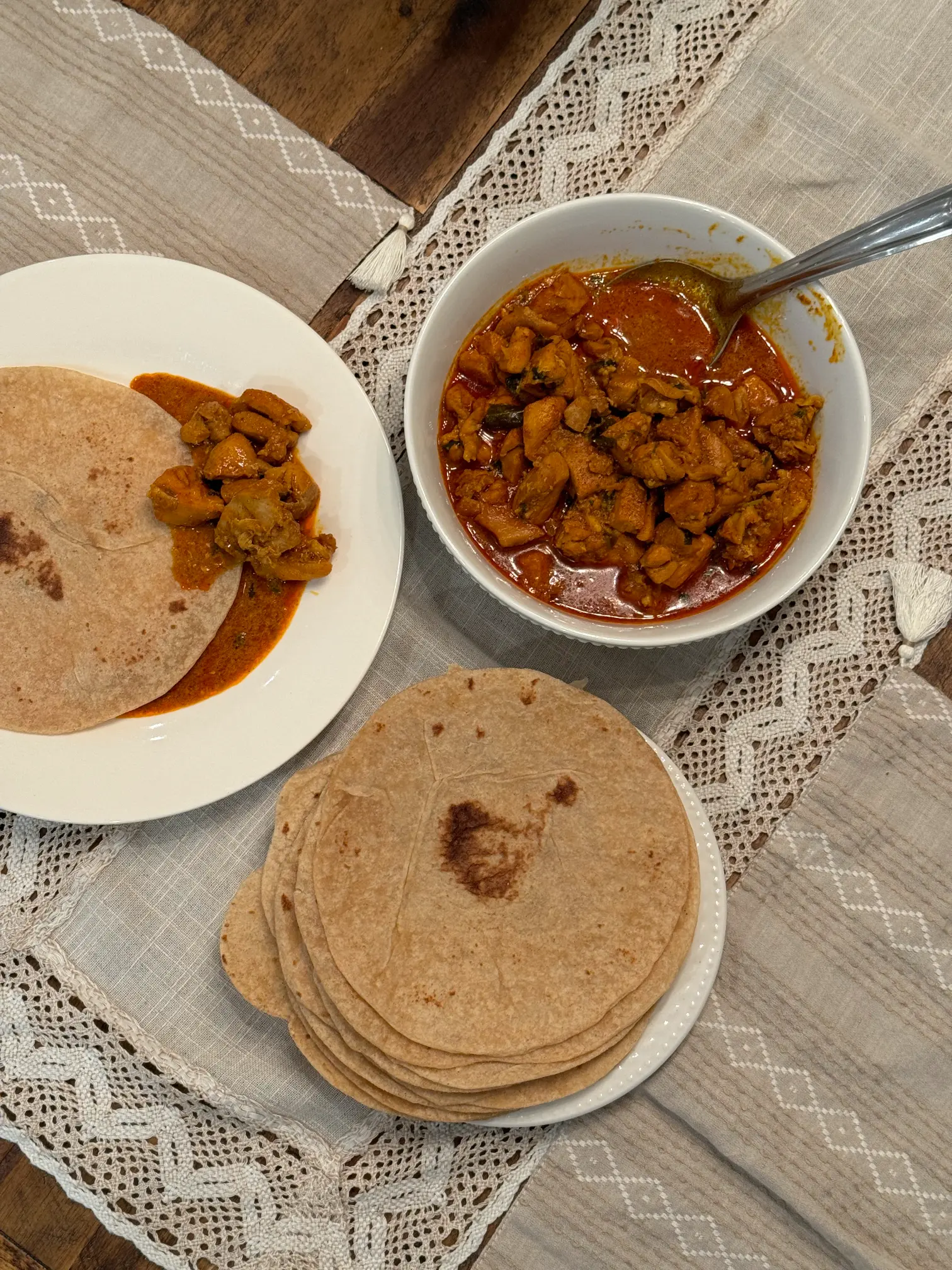 Marry Me chicken curry served in a white bowl on a table, accompanied by homemade chapatis.
